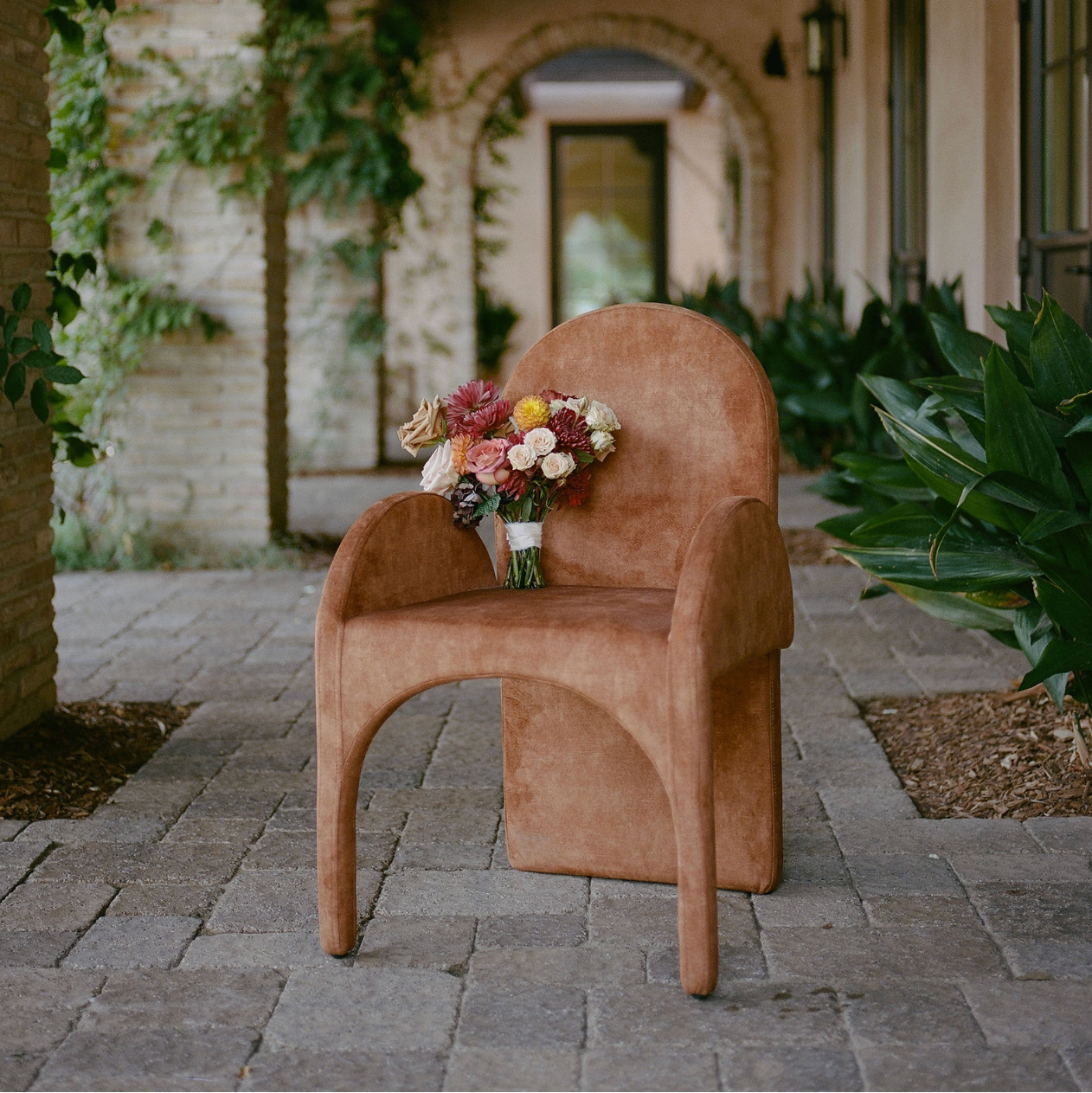 Brown chair with a bouquet of flowers on a stone patio